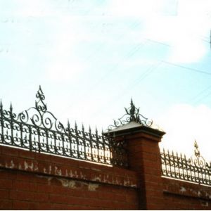 Забор, украшенный коваными колпаками и парапетом